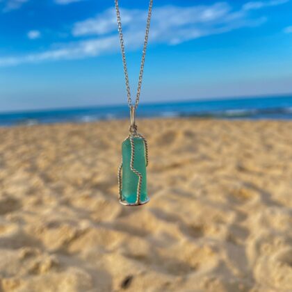 Handmade sea glass silver necklace with natural blue sea glass pendant reflecting light