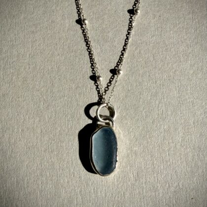 handmade blue sea glass silver necklace crafted in tunisia featuring a genuine blue sea glass pendant set in 925 sterling silver on a delicate silver chain , inspired by the Mediterranean sea .
